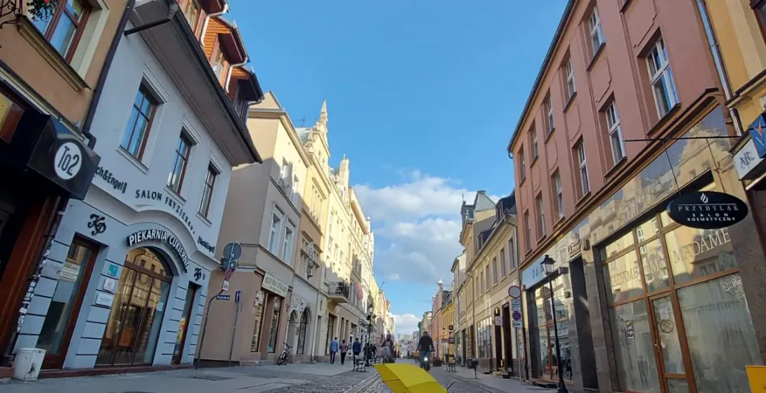 A yellow umbrella lies on a charming cobblestone street in a Polish city, surrounded by historic buildings.