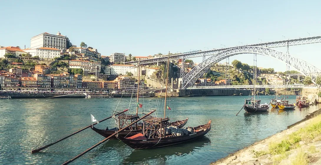 Traditional rabelo boats on the Douro River in Porto, Portugal, with the Dom Luís I Bridge in the background.