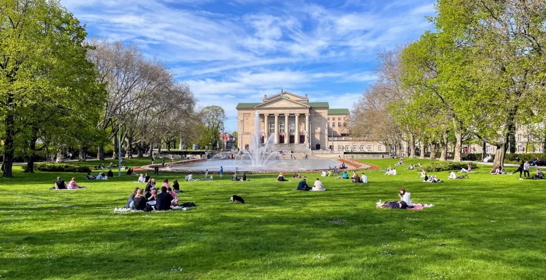 Relaxing scene in Poznań's park with the Grand Theatre in the background.