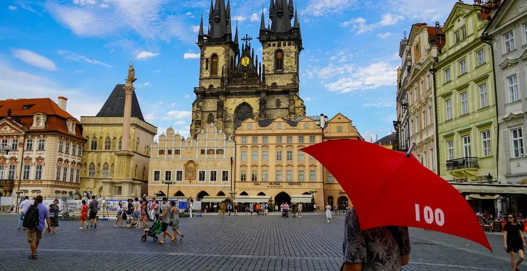 Tourists exploring Prague's Old Town Square, with the Church of Our Lady before Týn in the background.