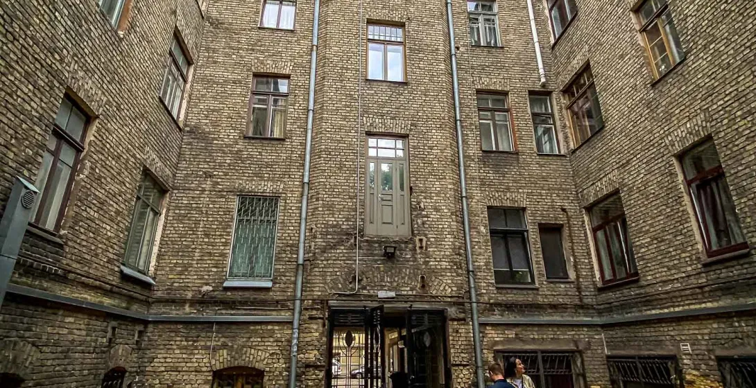 Tourists exploring a charming brick courtyard in Riga, Latvia.