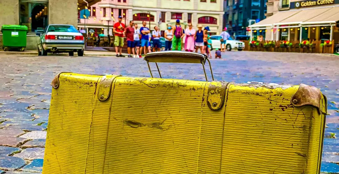 Vintage yellow suitcase on a cobblestone street in Riga, Latvia.