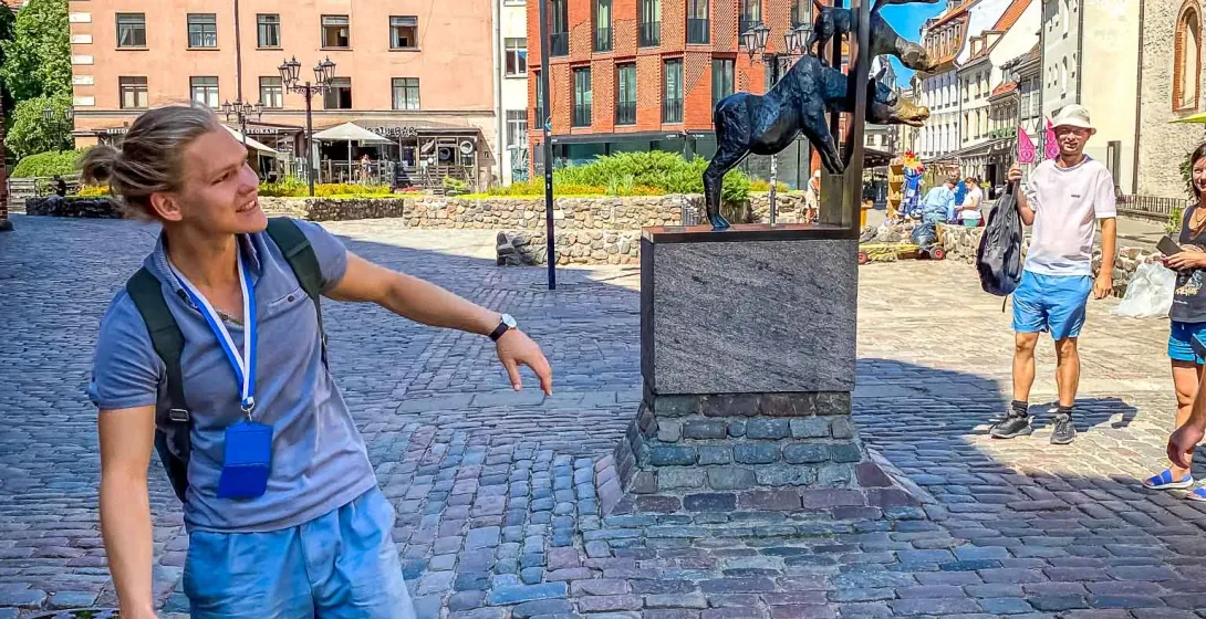 A tour guide in Riga, Latvia, points to a unique bronze sculpture in a cobblestone square.
