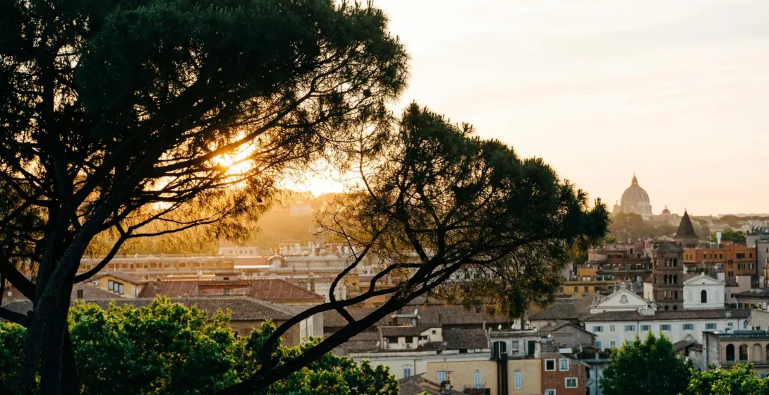 Sunset view of Rome, Italy, with St. Peter's Basilica in the distance.
