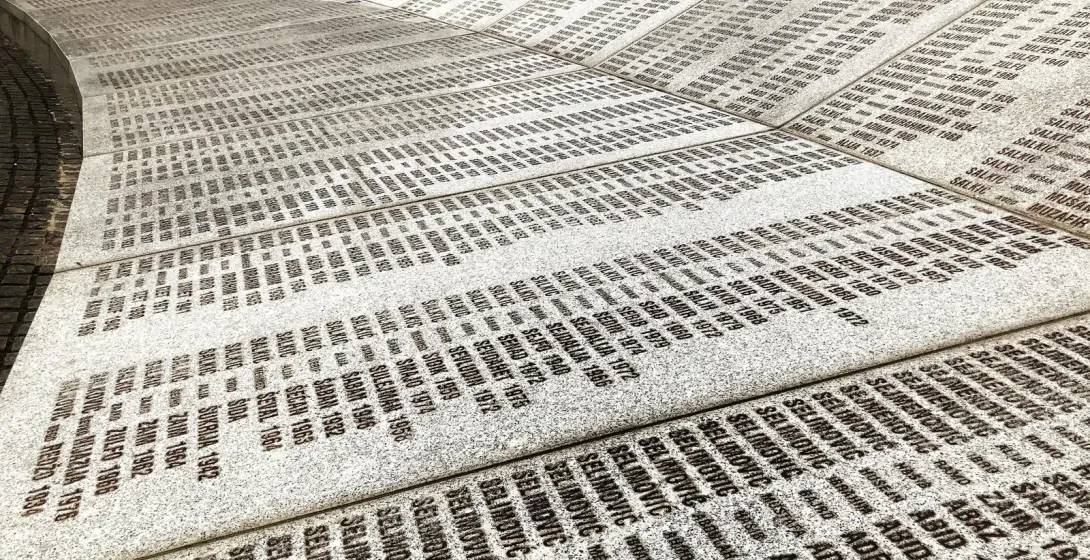 A curved memorial wall inscribed with numerous names and dates.
