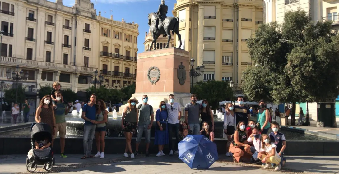 A tour group in Seville, Spain, poses in front of an equestrian statue.