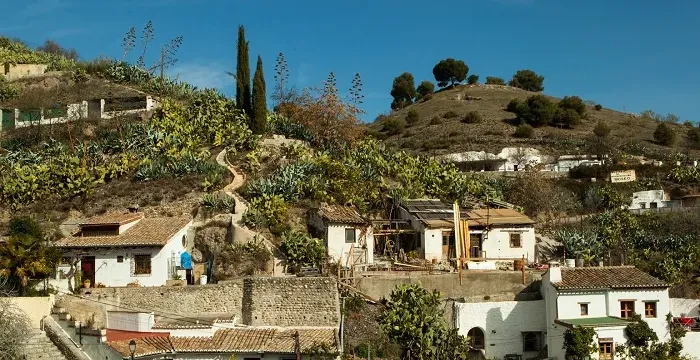 Charming hillside town in Spain with whitewashed houses and lush vegetation.