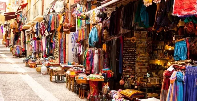 Colorful street market in Spain, filled with textiles and souvenirs.