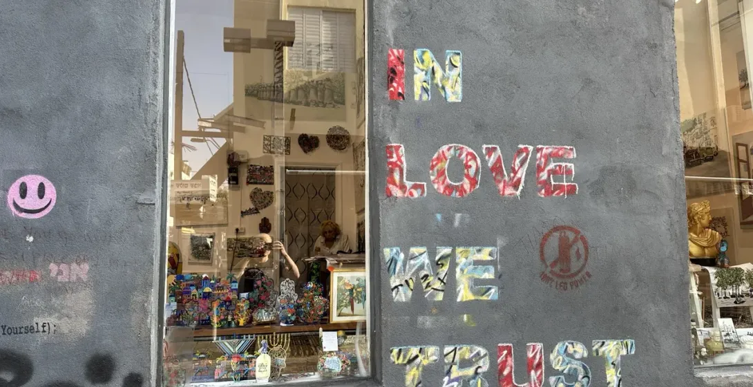 Colorful street art in Tel Aviv, Israel, next to a shop window displaying unique handicrafts.