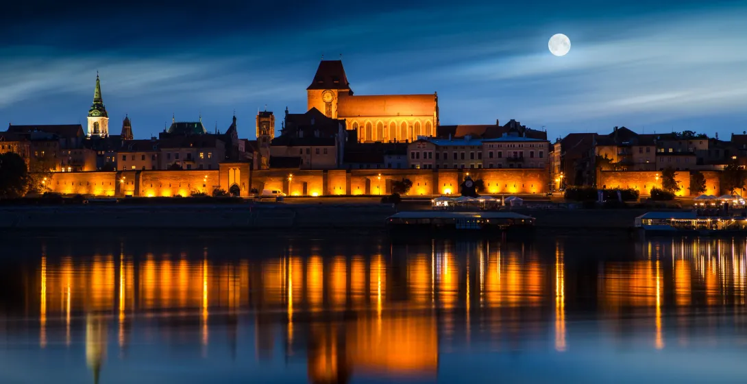 Night view of Toruń's Old Town, Poland, reflecting in the Vistula River.