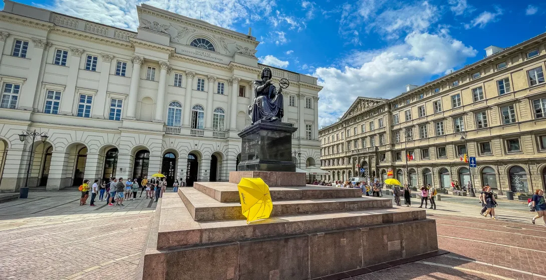 Tourists explore the Copernicus Monument in Warsaw's Old Town.