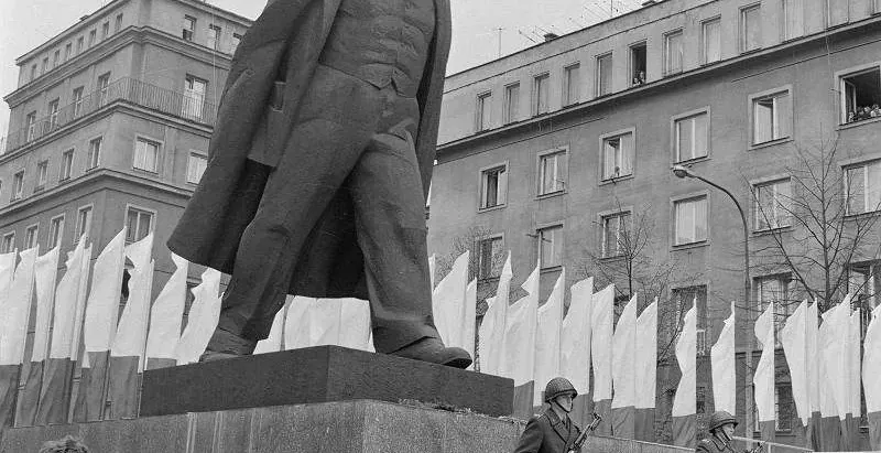 A large statue of Lenin in Warsaw, Poland, guarded by soldiers.