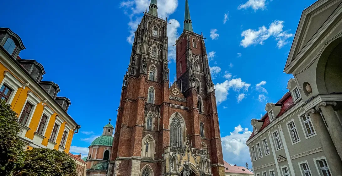 Wrocław Cathedral, a stunning Gothic landmark, stands tall against a vibrant blue sky.