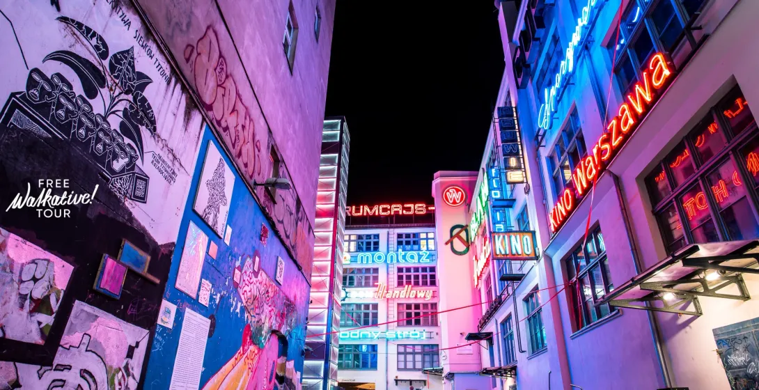 Vibrant Wrocław alley at night, showcasing street art and neon signs.