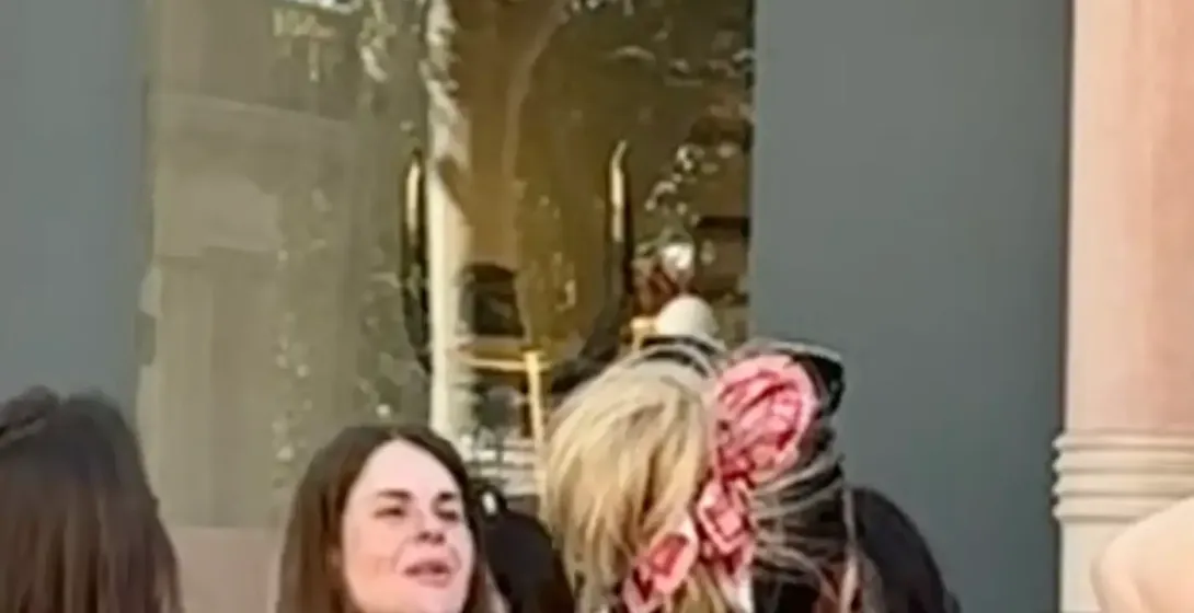 People on a street in Barcelona, with a Loewe store facade featuring ornate architectural details, balconies, and reflecti...