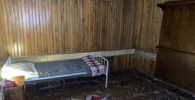 A simple historical room with a single bed and wooden walls.
