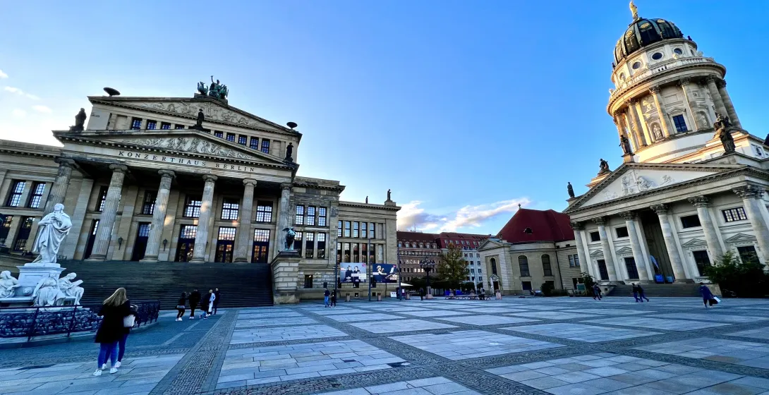 View of Gendarmenmarkt in Berlin with the Konzerthaus (left) and Deutscher Dom (right) under a clear blue sky.