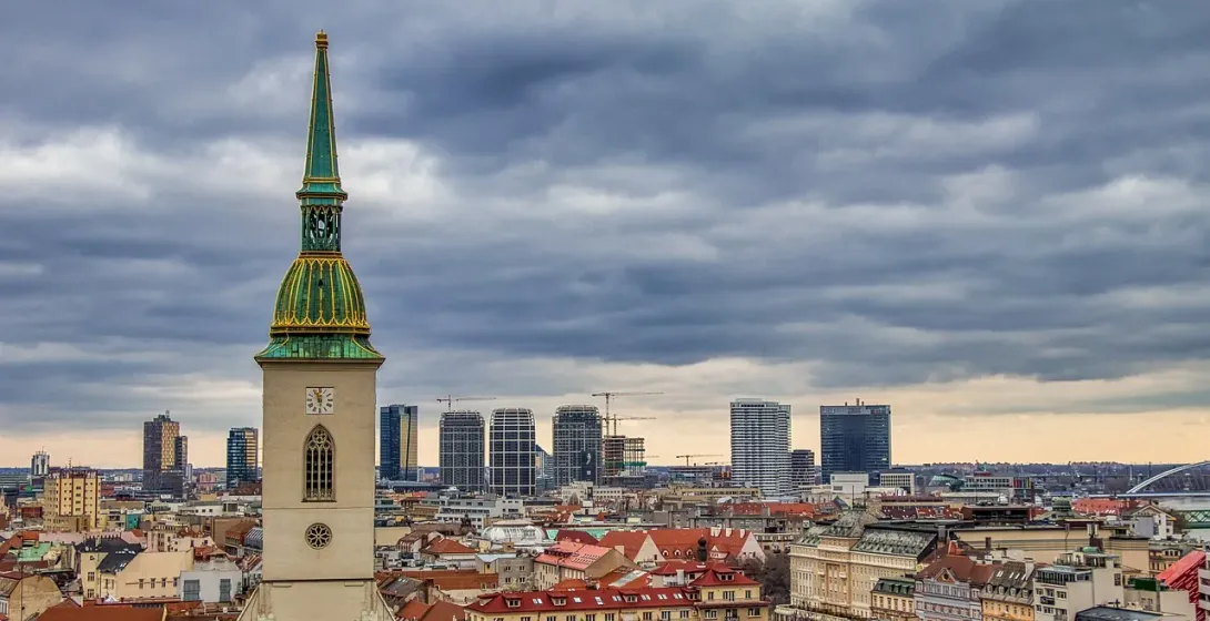 St. Martin's Cathedral tower with green spire and clock face overlooking Bratislava's old town and modern city skyline und...