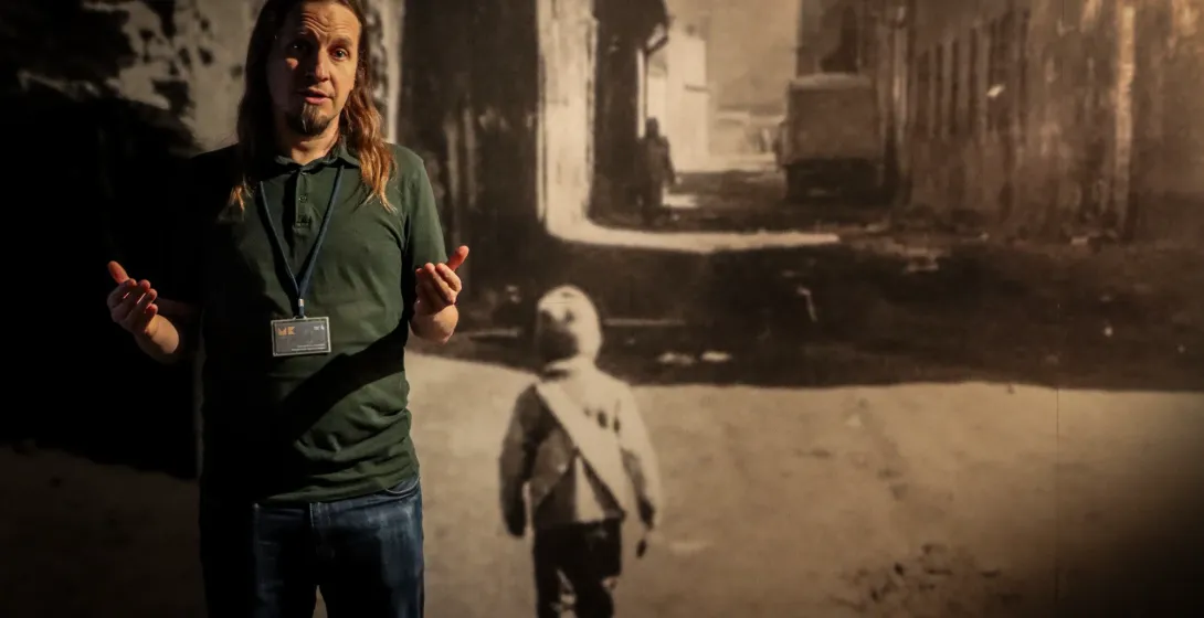 A tour guide speaks in front of a historical photo exhibit at Schindler's Factory Museum in Krakow.