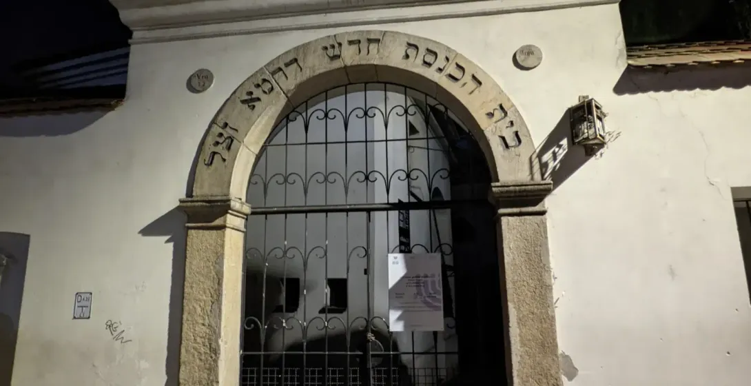 Stone entrance to the Isaak Synagogue in Krakow's Kazimierz district at night, with Hebrew script over an arched gate.