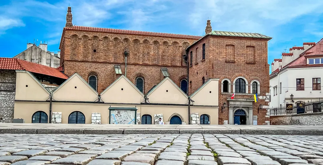 Low angle view of the historic Old Synagogue in Kazimierz, Krakow, with focus on cobblestone foreground.