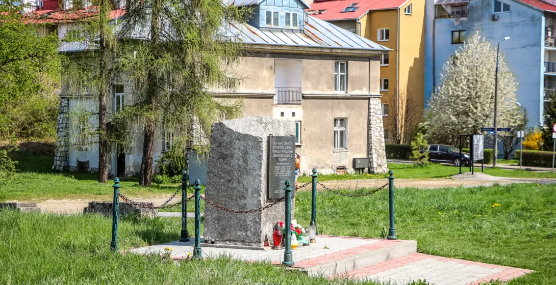 A stone memorial in a grassy area in front of the historic Grey House at the former Płaszów camp site in Krakow.
