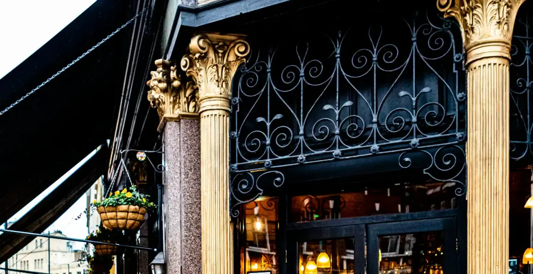 Ornate black and gold entrance to The Ten Bells pub on a London street, with its sign displayed above.