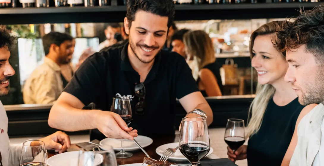 A group of friends shares food and red wine at a table in a Madrid tapas bar.