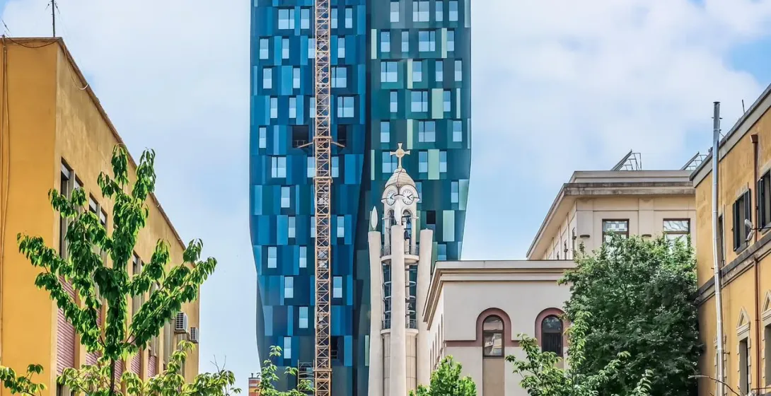 Modern skyscraper and historic building in a city.