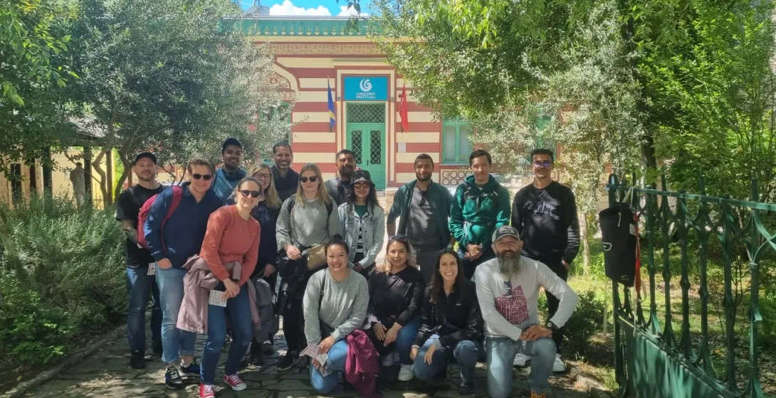 Happy tourists on a group tour pose for a photo in front of a beautiful building.