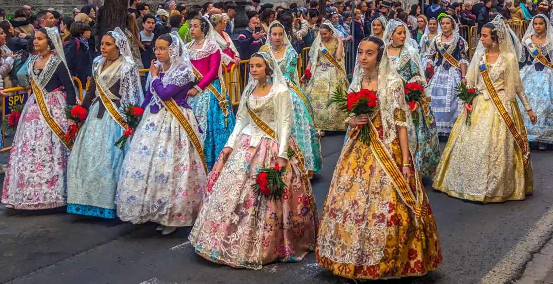 A group of women and girls in colourful, traditional Fallera dresses during a street parade in Valencia.