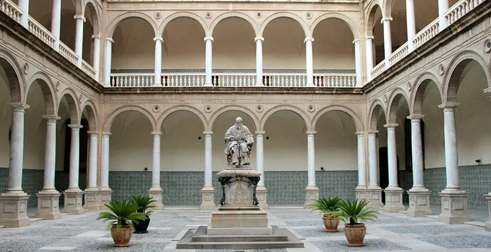 Statue in the courtyard of the Real Colegio del Patriarca in Valencia, surrounded by a two-story arched colonnade.