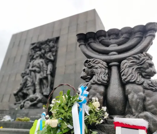 Warsaw Ghetto Memorial with menorah and flowers.