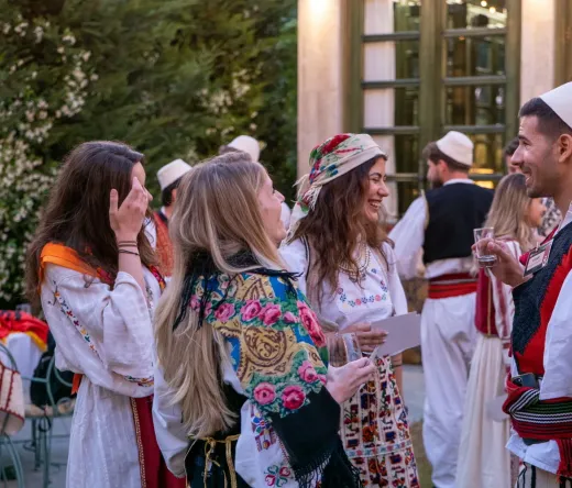 Tourists enjoying an Albanian Night show, interacting with performers in traditional clothing.