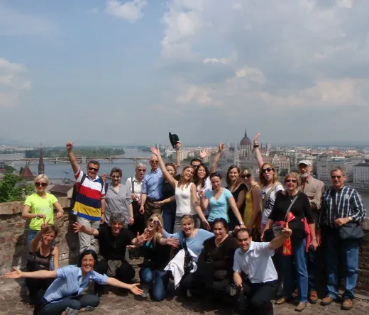 Happy tour group in Budapest, Hungary, with the Parliament Building in the background.