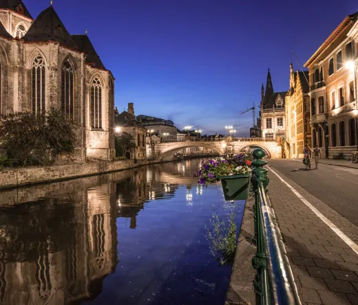 Ghent's charming canal at night, reflecting historic buildings.
