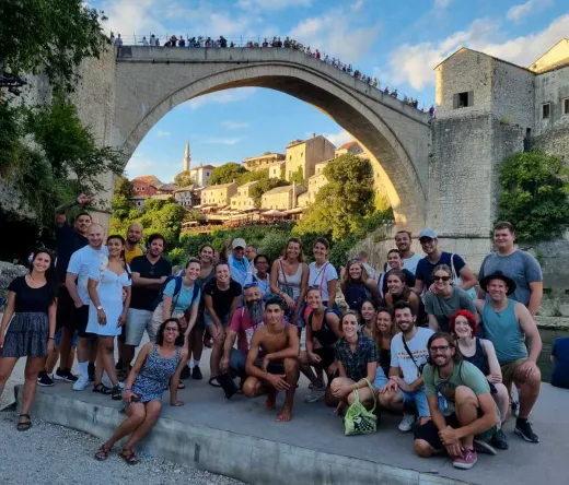 Happy tour group in Mostar, Bosnia and Herzegovina, posing with the Stari Most bridge.