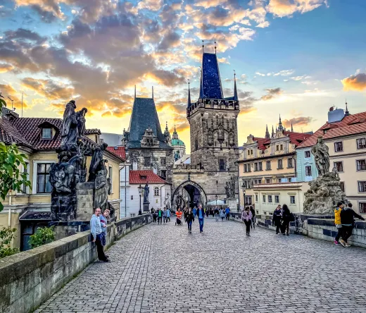 Tourists enjoying a sunset stroll across Prague's Charles Bridge.