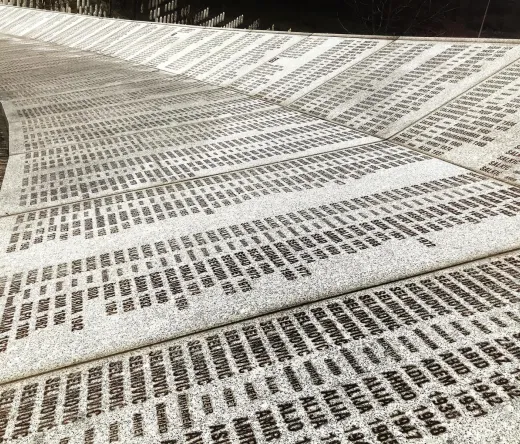 A curved memorial wall inscribed with numerous names and dates.