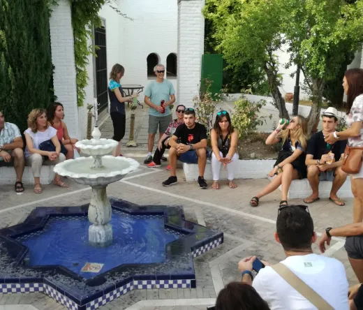 A tour group listens attentively to their guide in a beautiful Seville courtyard.