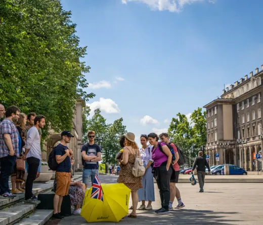 A guided tour group explores a sunny city square in Krakow, Poland.