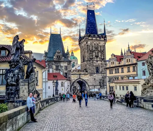 Tourists enjoying a sunset stroll across Prague's Charles Bridge.