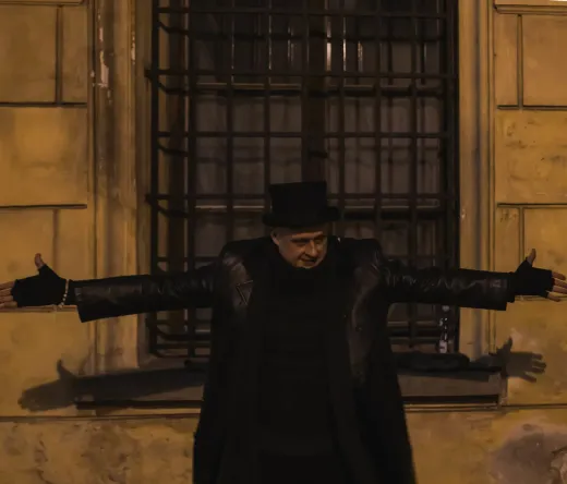 Tour guide in top hat in front of old building.