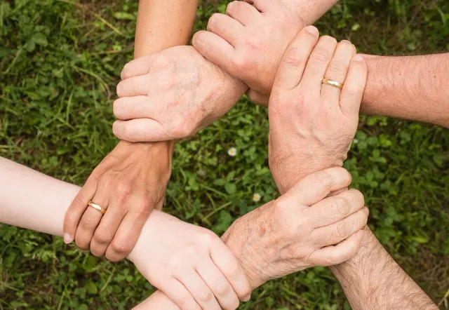 Hands clasped together in a circle, symbolizing unity and teamwork on a group tour in Gdansk.
