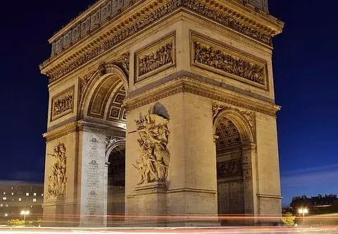 The Arc de Triomphe in Paris at night, illuminated beautifully.