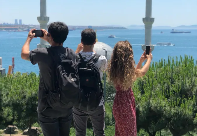 Tourists taking photos of a beautiful mosque and the Bosphorus in Istanbul.