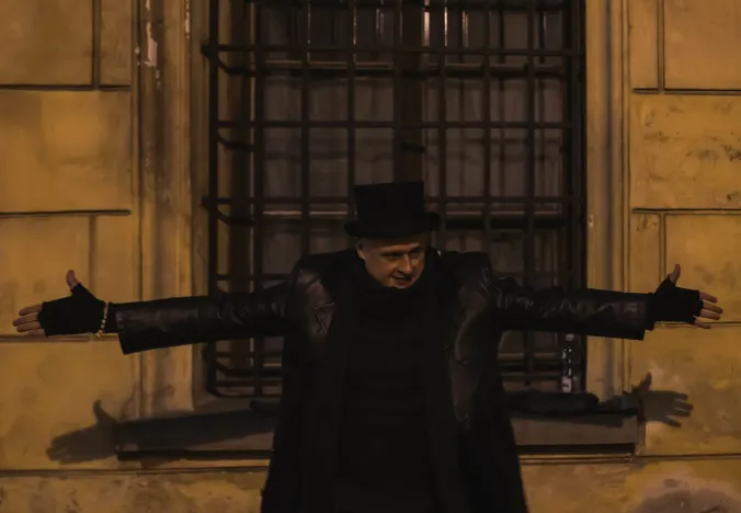 Tour guide in top hat in front of old building.