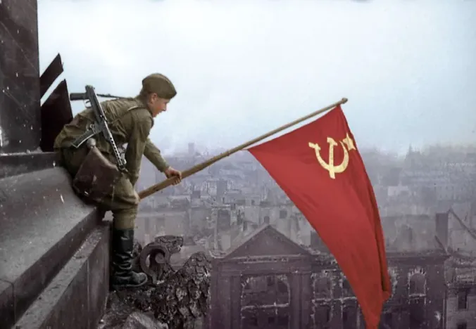 Soviet soldier raising a flag in war-torn Berlin.