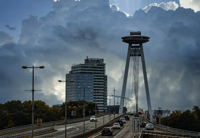 Dramatic view of Bratislava's UFO Bridge and observation tower under a stormy sky.