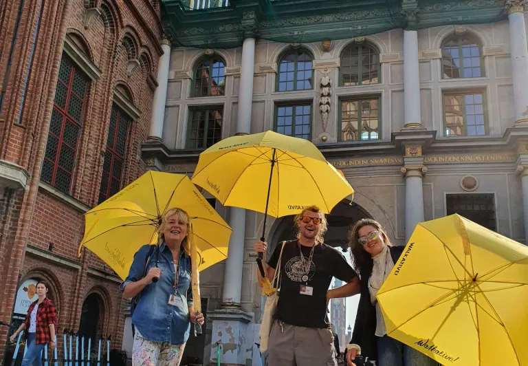Happy tourists on a guided tour in Gdansk, Poland, standing in front of the Golden Gate.